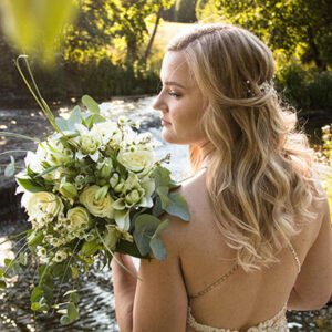 Tagasiside foto. Pulmad. Naine toetab kimpu õlale ja vaatab seda.